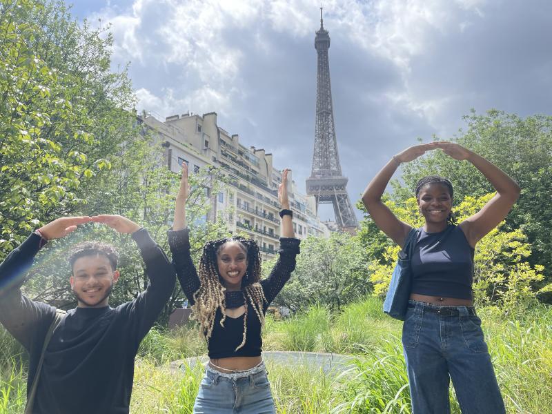 Three students posing in the O-H-I-O in front of the Eiffel Tower
