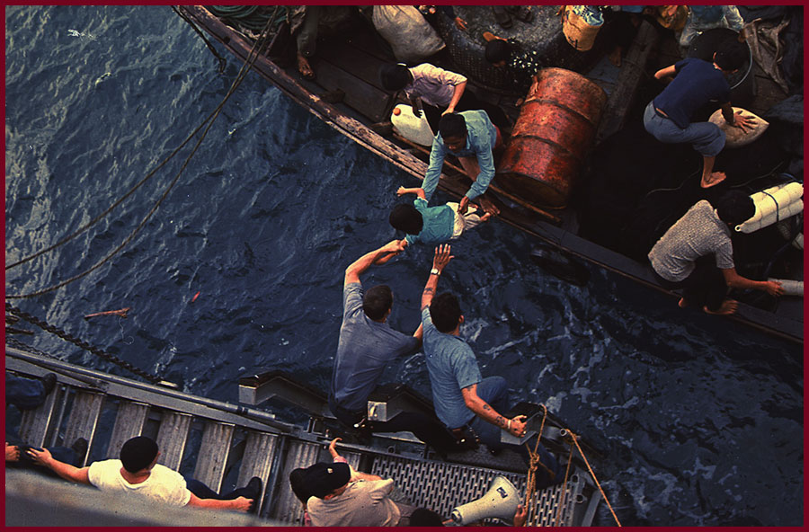 Crew on the USS Durham help Vietnamese refugees from a small craft onto their vessel in the South China Sea, 1975. Public Domain.