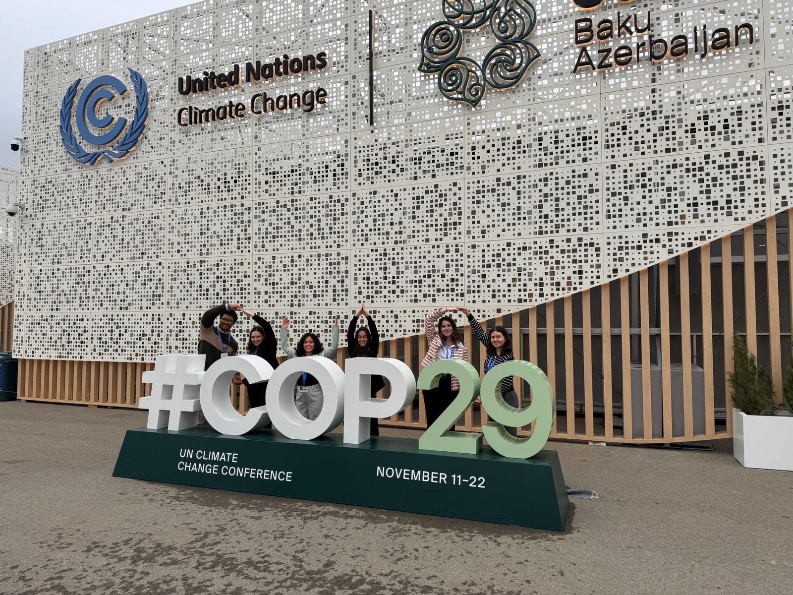 Ohio State students standing behind COP29 sign forming O-H-I-O