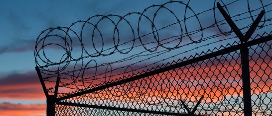 Razorwire fence silhouetted at sunset