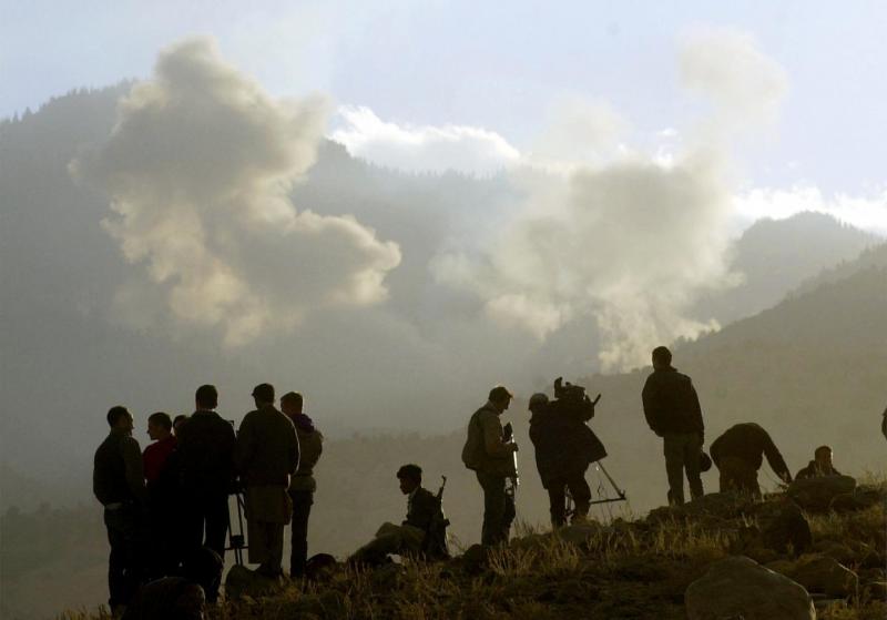 Journalists and anti-Taliban and soldiers watch plumes rise from bombs dropped on Al Qaeda positions by American bombers December 15, 2001 in the Tora Bora area of Afghanistan.