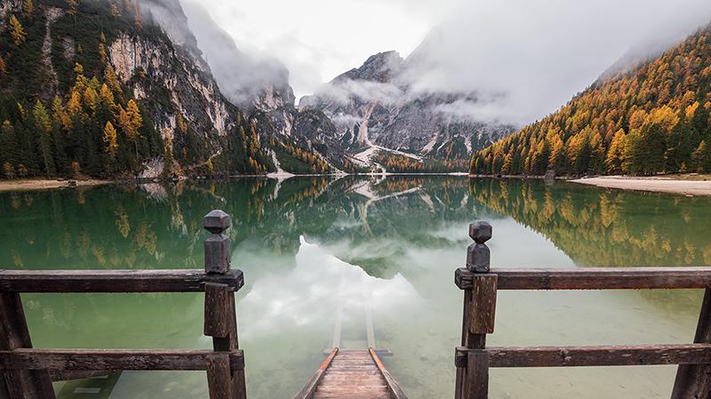 lake with fence in foreground and mountains in background