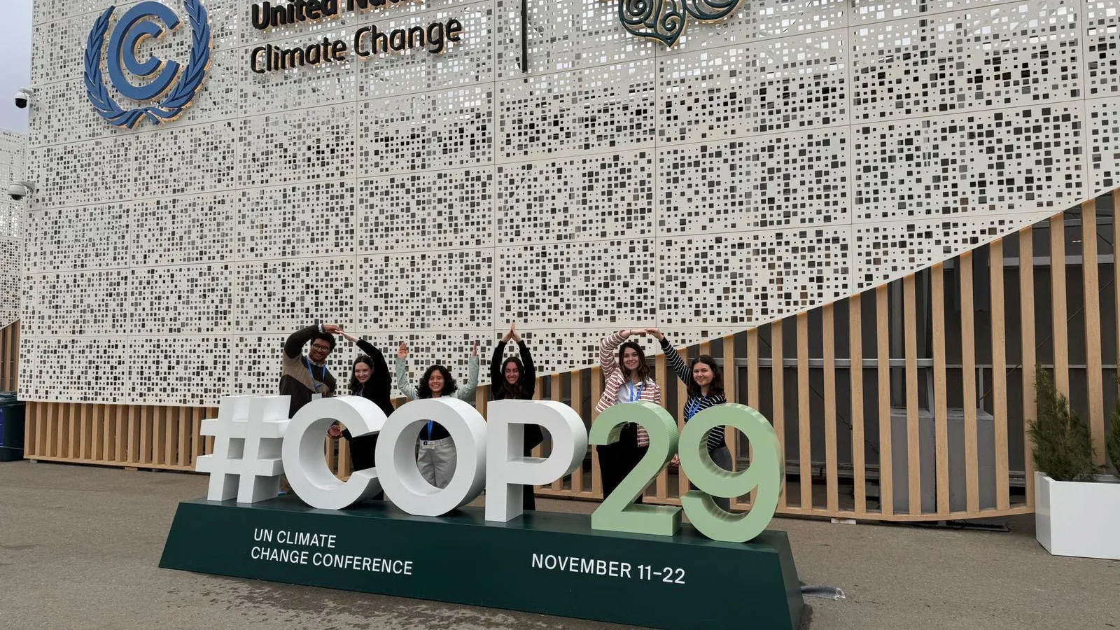 Ohio State students standing behind COP29 sign forming O-H-I-O