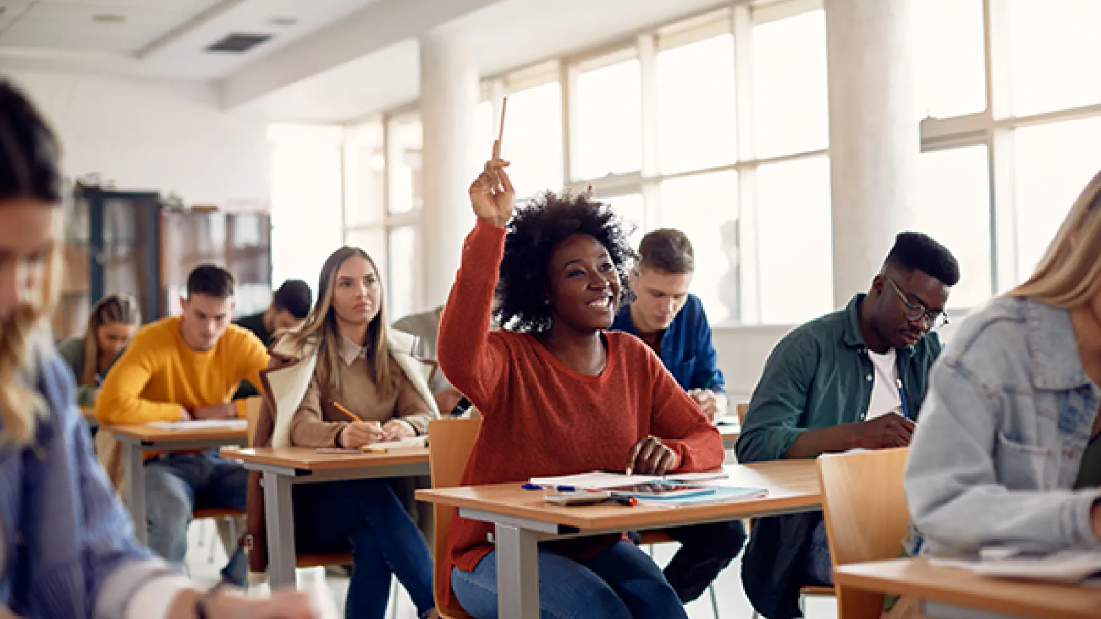 students sitting at desks in a classroom, one student had her hand raised