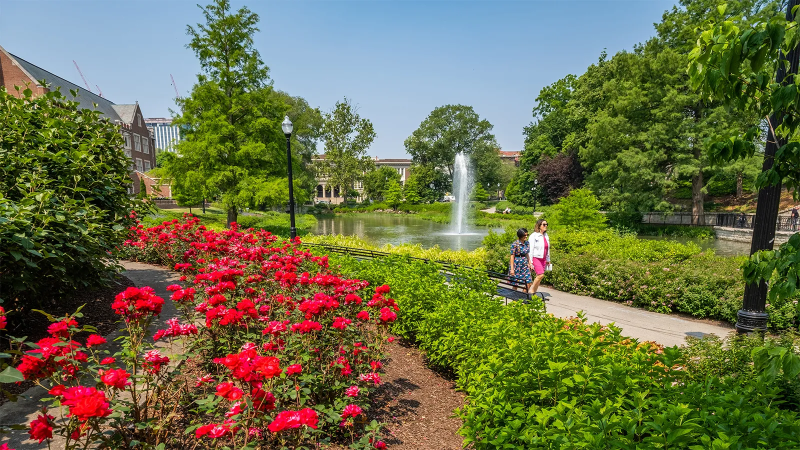 Students walking past flowers and Mirror Lake at Ohio State
