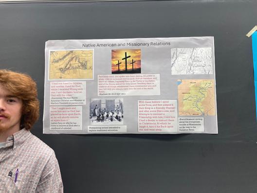 a male student standing in front of his poster