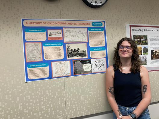 a student standing in front of a poster