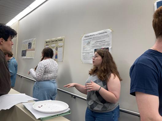 a student stands in front of her poster