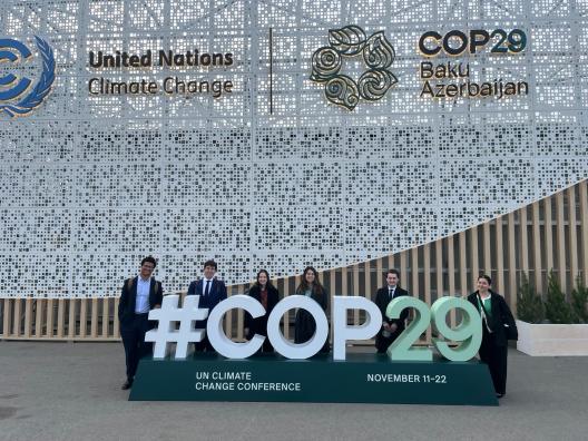 Students behind a sign that reads #COP29