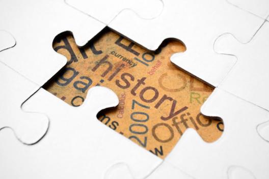 The word history written on parchment under a puzzle piece.