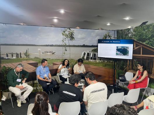 people sitting in chairs in front of a large monitor