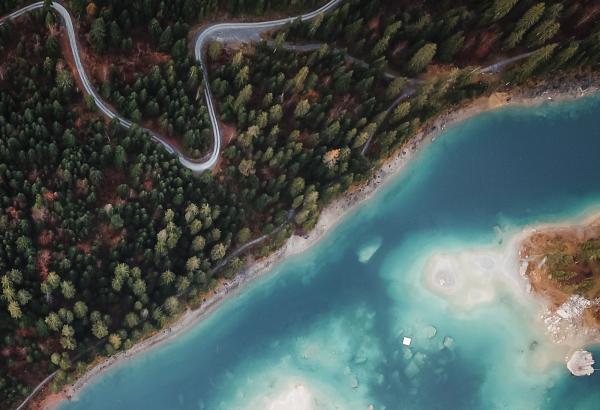 a lake and forest with a curvy highway