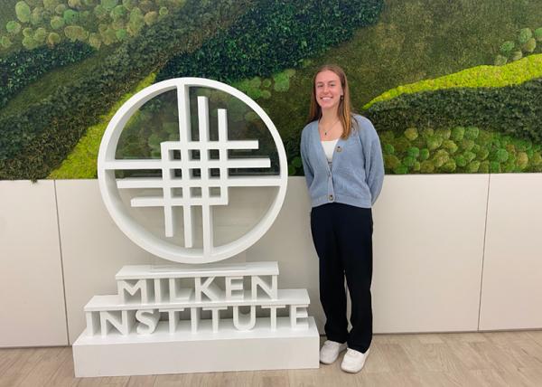 Amelia Figler standing next to a Milken Institute sign