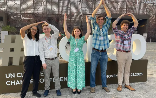 five OSU students and staff spelling Ohio in front of the COP30 building in Brazil