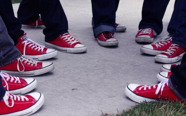 seven people's feet wearing red tennis shoes