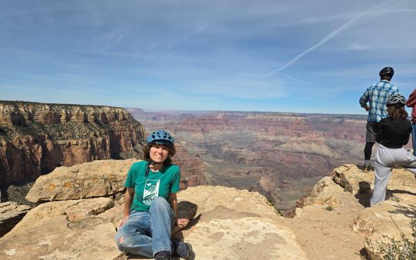 Undergraduate student Anna Elfers sitting on a rock in front of the Grand Canyon