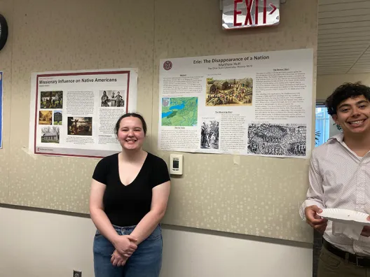 two students standing in front of posters