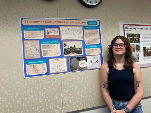 a student standing in front of a poster