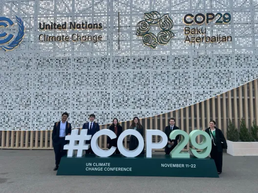 Students behind a sign that reads #COP29