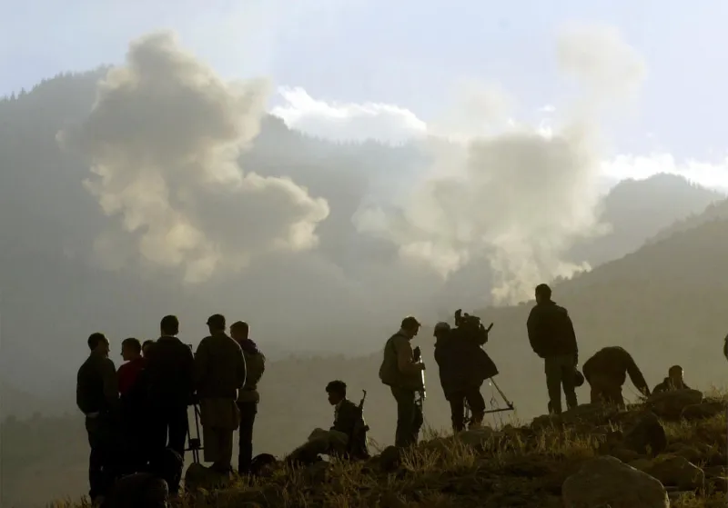 Journalists and anti-Taliban and soldiers watch plumes rise from bombs dropped on Al Qaeda positions by American bombers December 15, 2001 in the Tora Bora area of Afghanistan.