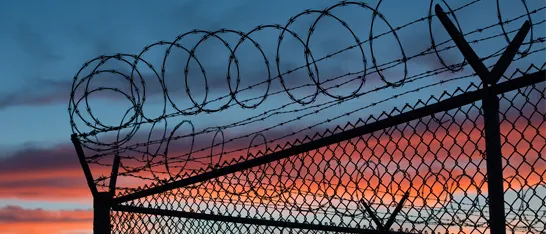Razorwire fence silhouetted at sunset
