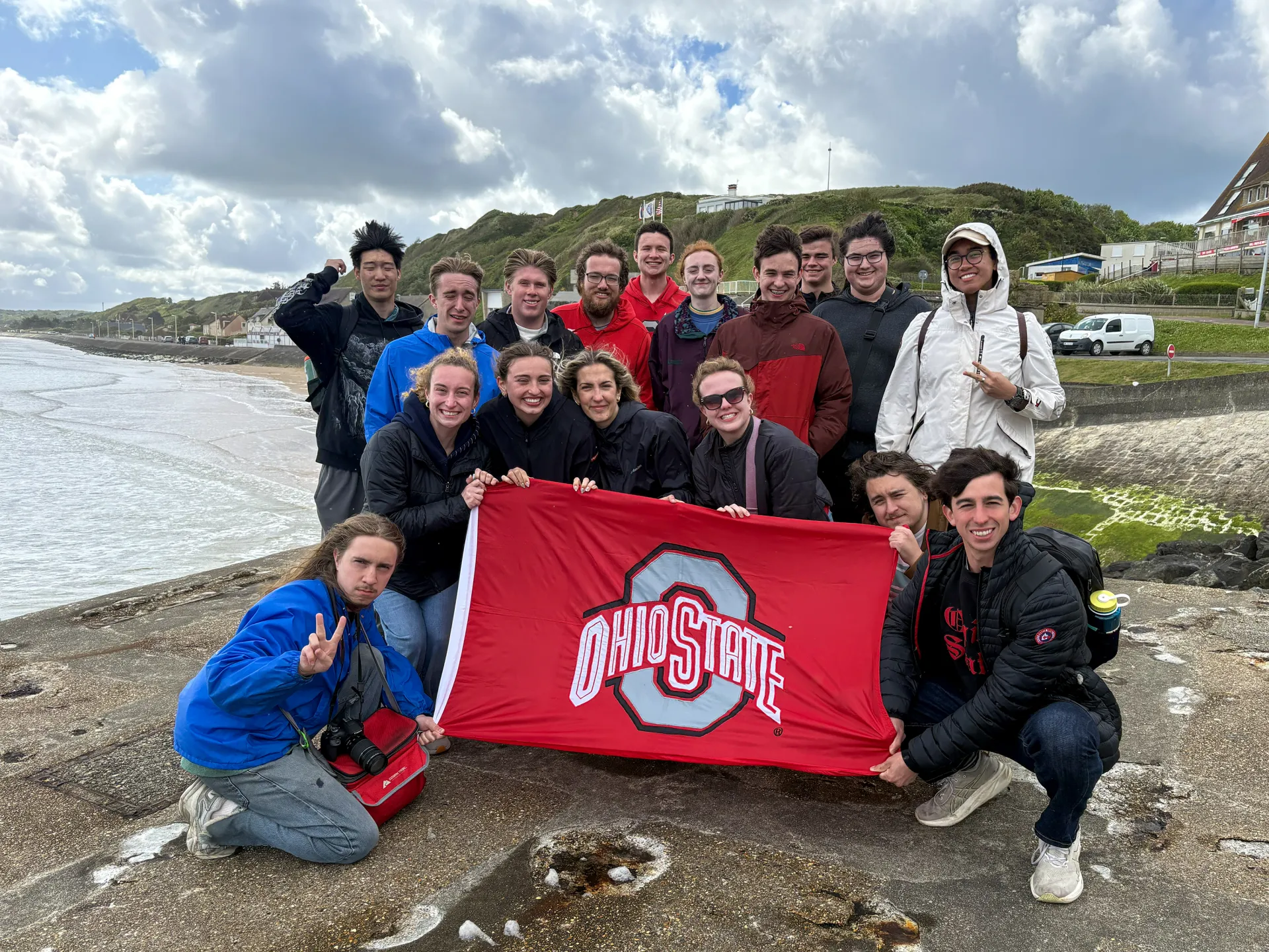 A group of students holding an Ohio State University flag at Omaha Beach