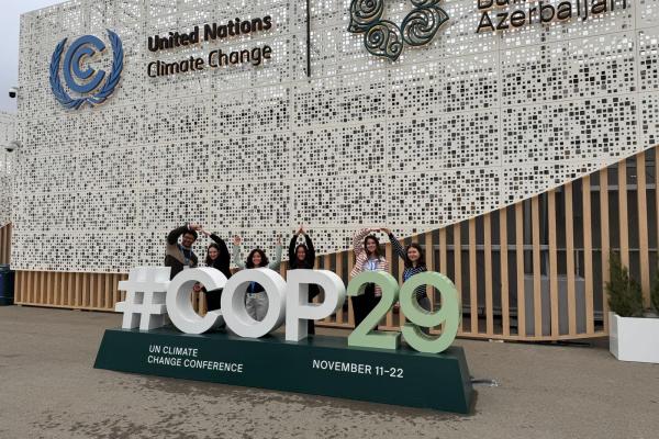 Ohio State students standing behind COP29 sign forming O-H-I-O