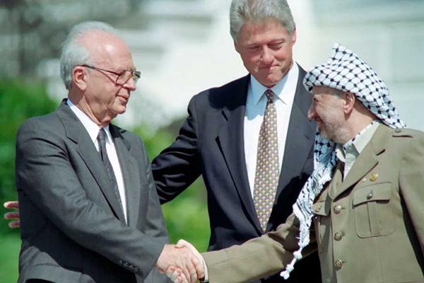 US President Bill Clinton (C) stands between PLO leader Yasser Arafat (R) and Israeli Prime Minister Yitzahk Rabin (L) as they shake hands for the first time, on Sept. 13, 1993 at the White House in Washington, D.C., after signing the historic Israel-PLO Oslo Accords on Palestinian autonomy in the occupied territories.J. David Ake—AFP / Getty Images