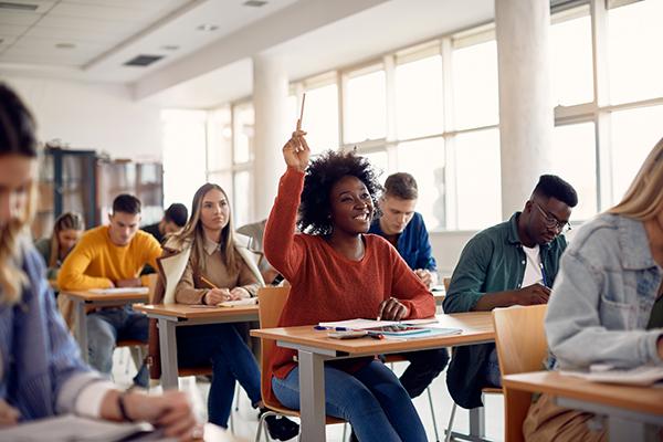 students sitting at desks in a classroom, one student had her hand raised