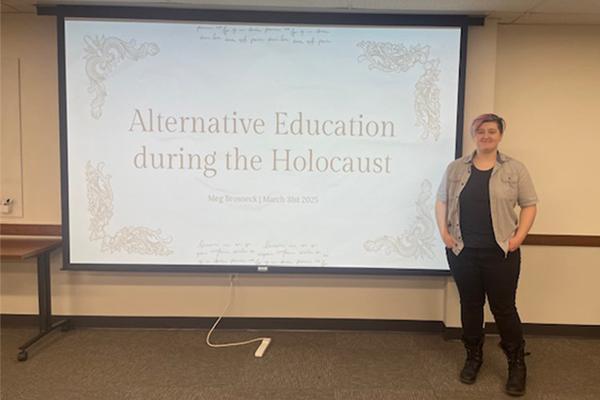 Meg Brosneck standing in front of a title slide of her thesis