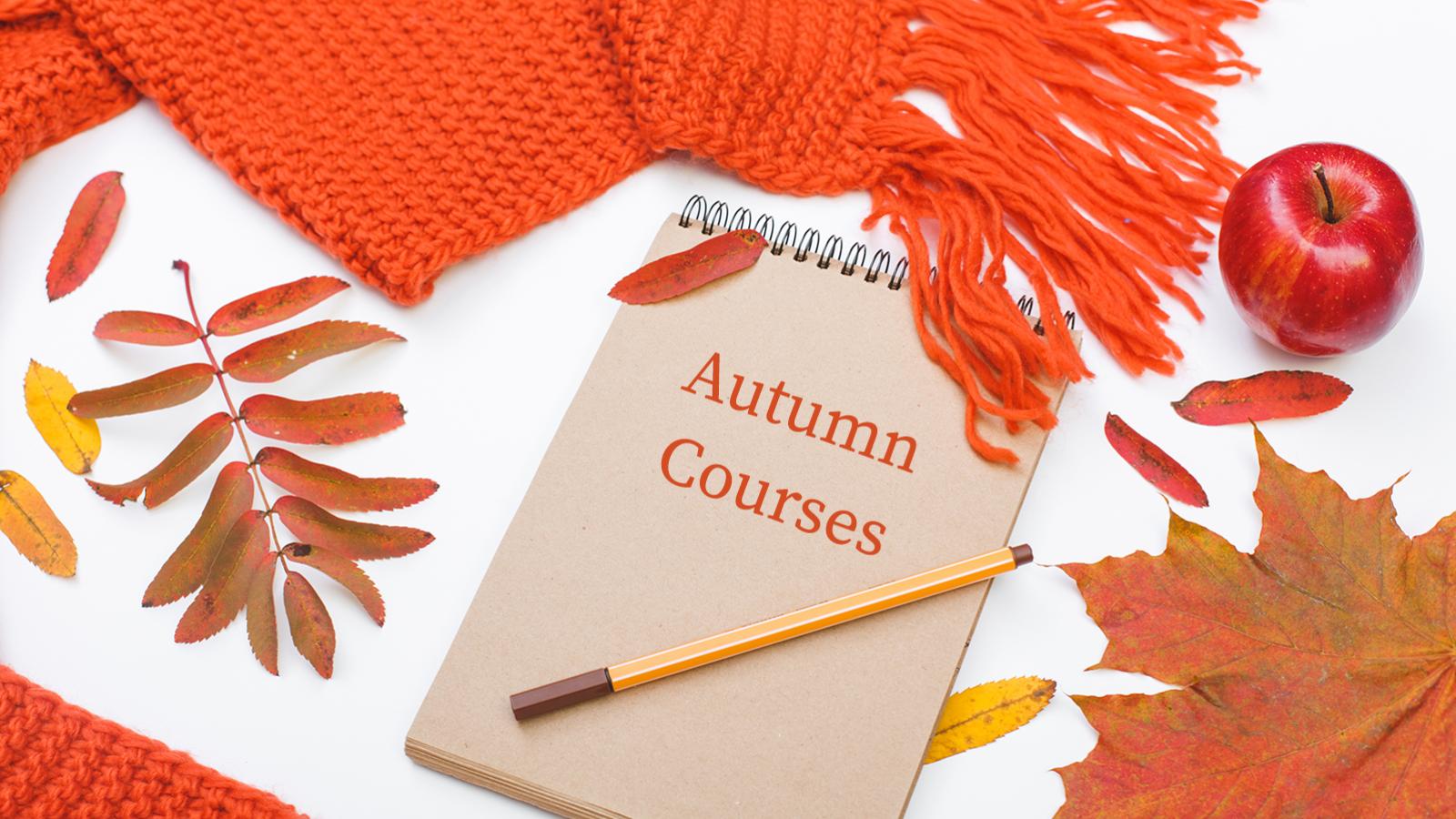 autumn courses written on pad of paper, pencil, leaves, apple and orange knitted scarf