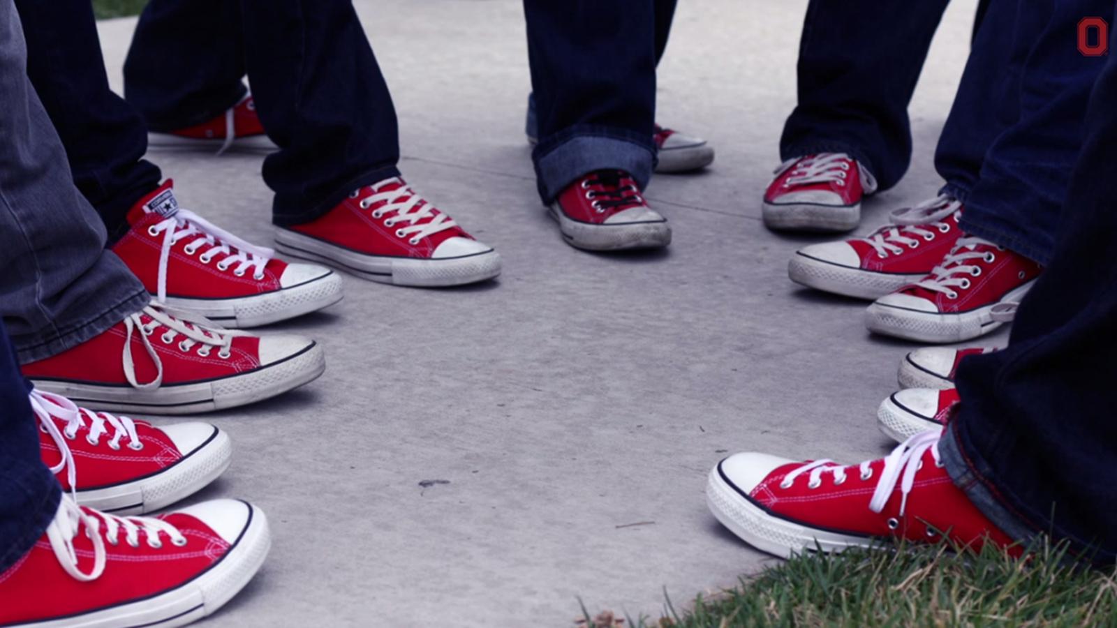 seven sets of people's feet wearing red tennis shoes