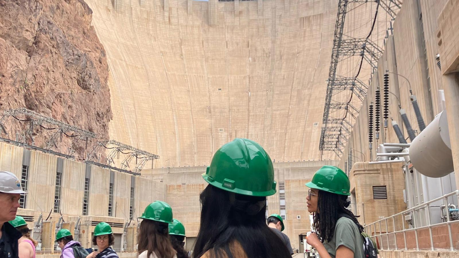 students on a tour at the Hoover Dam in green hard hats 