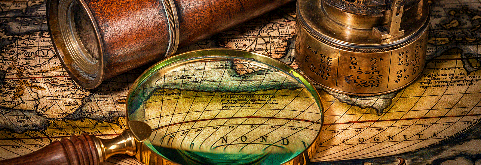 antique map with antique spy glass, compass and magnifying glass laying on top of it